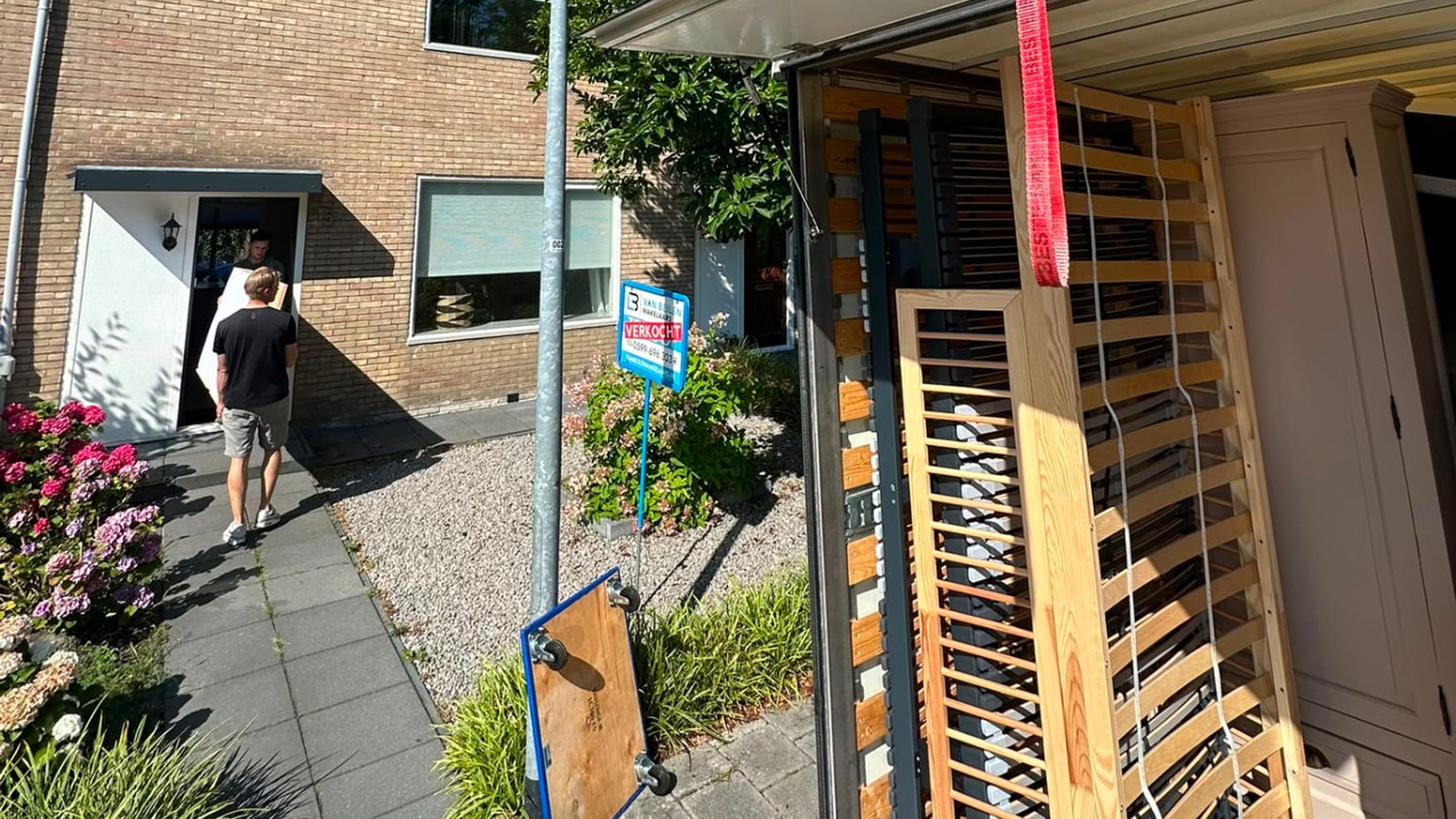Verhuizers van JF Transport en Verhuizing dragen een bedbodem naar de verhuiswagen bij een verkochte woning in Groningen